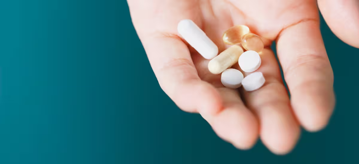 Nahrungsergänzungsmittel in Tablettenform auf der Handfläche|Frau mit Primabiotic Nahrungsergänzungsmittel