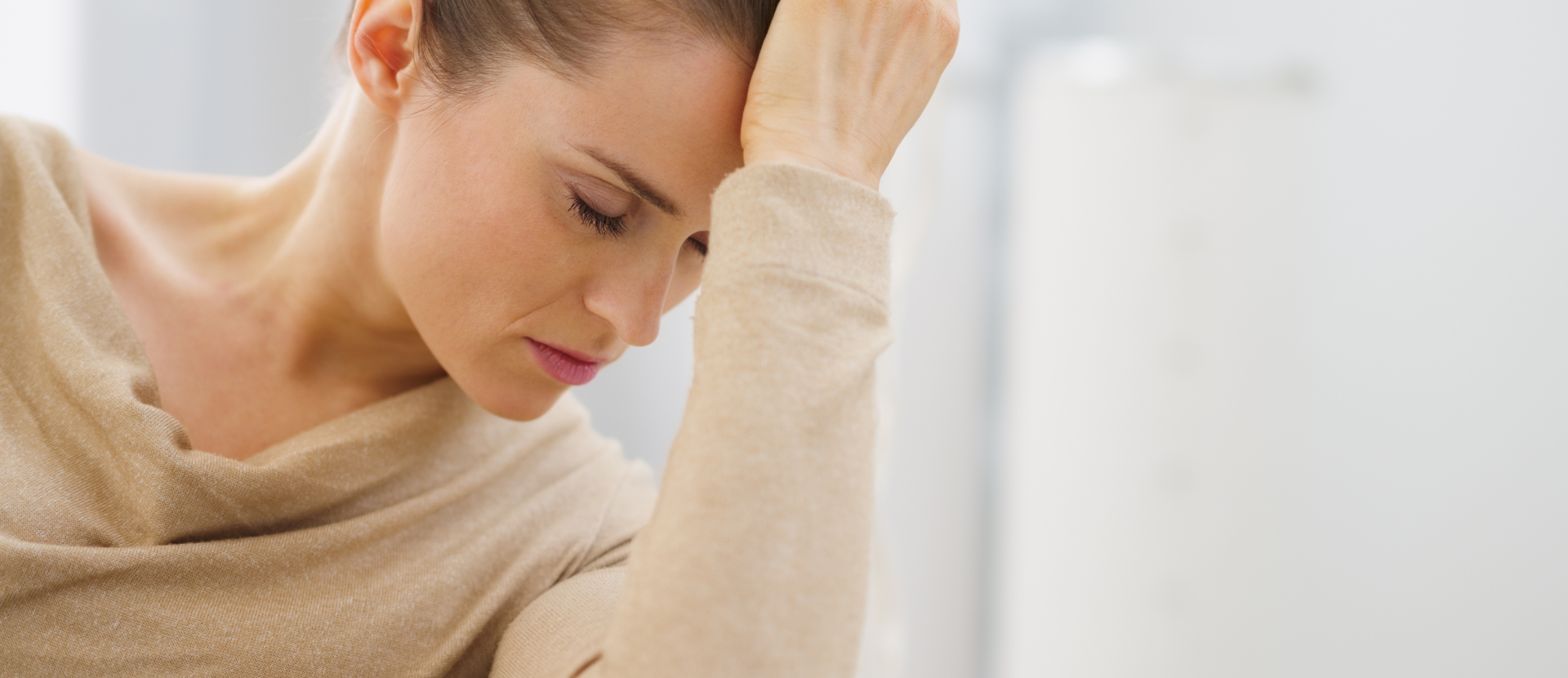 Nachdenkliche Frau stützt den Kopf auf die Hand und wirkt erschöpft oder gestresst