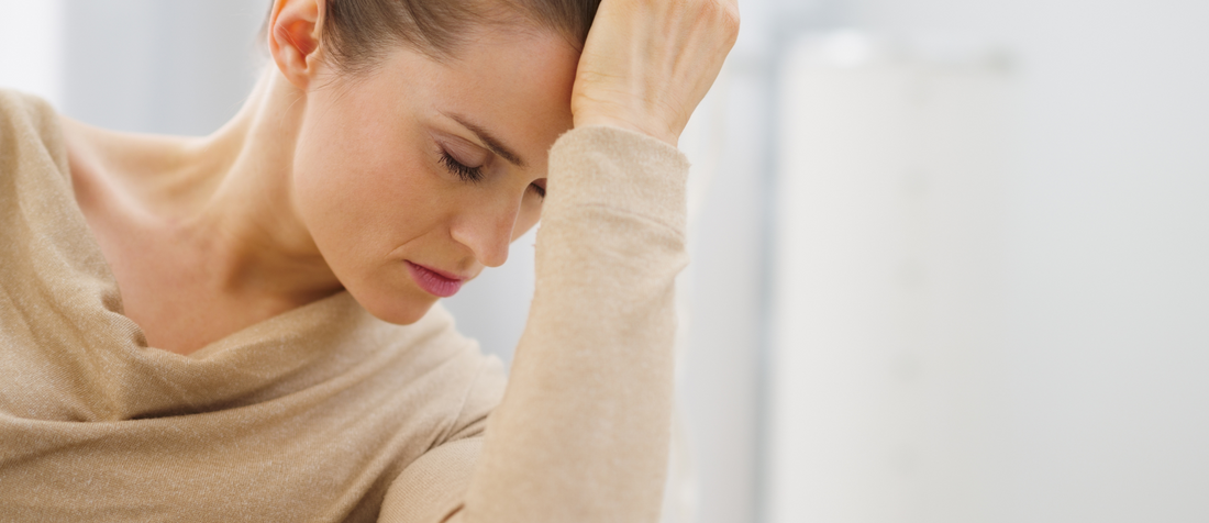 Nachdenkliche Frau stützt den Kopf auf die Hand und wirkt erschöpft oder gestresst