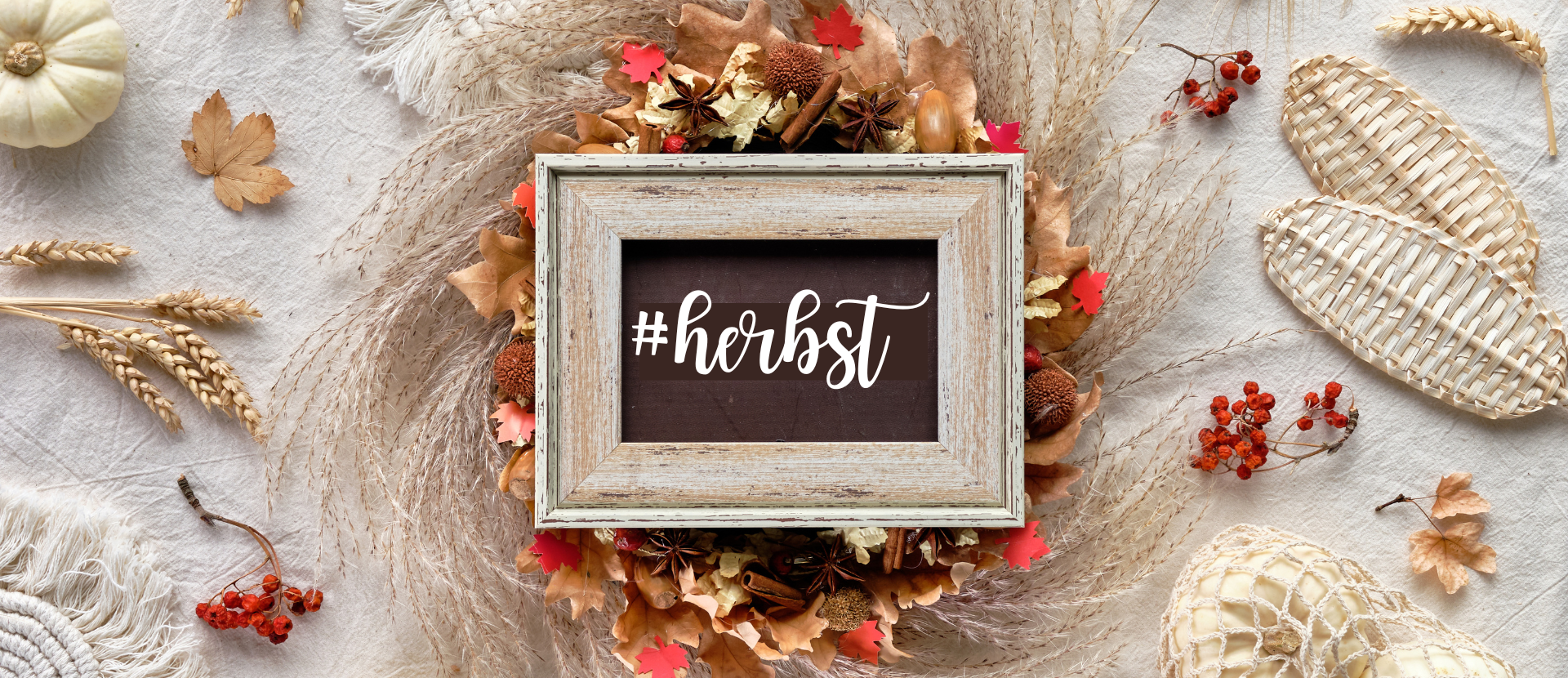 Herbstdekoration mit Bilderrahmen und Schriftzug „#herbst“, umgeben von Blättern und Ähren