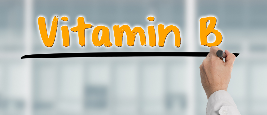 Hand eines Arztes unterstreicht den orangefarbenen Schriftzug „Vitamin B“ auf Glaswand