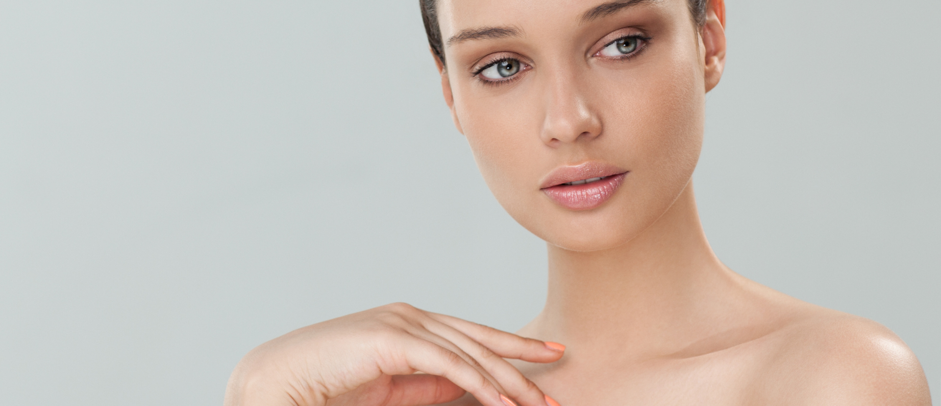 Junge Frau mit glatter, strahlender Haut und natürlichem Make-up blickt sanft zur Seite