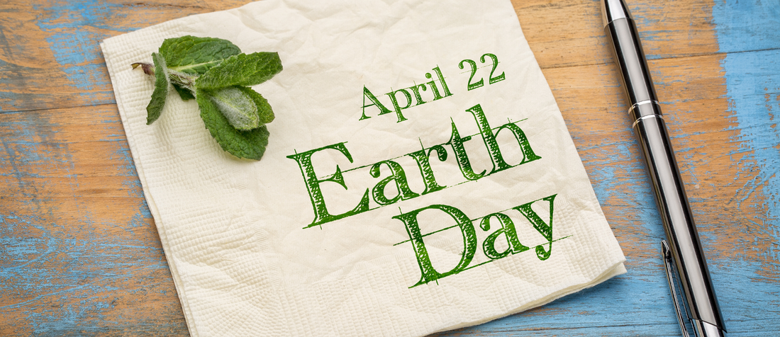 Serviette mit Aufschrift „Earth Day April 22“ auf Holztisch neben Stift und Minzblättern