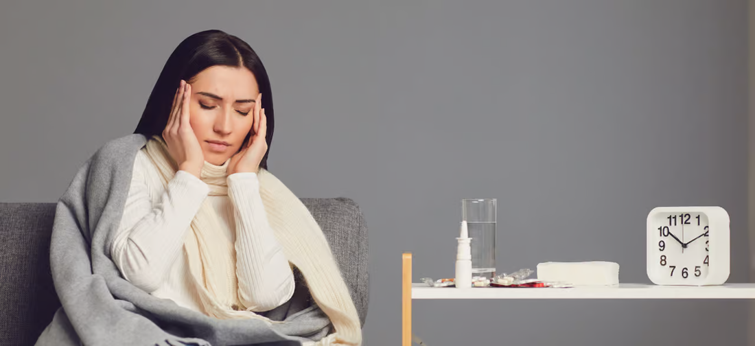 Frau mit Erkältung hält sich den Kopf