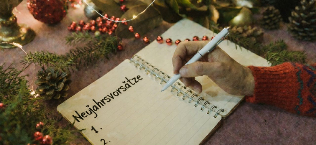 Mann schreibt Neujahrsvorsätze in ein Notizbuch