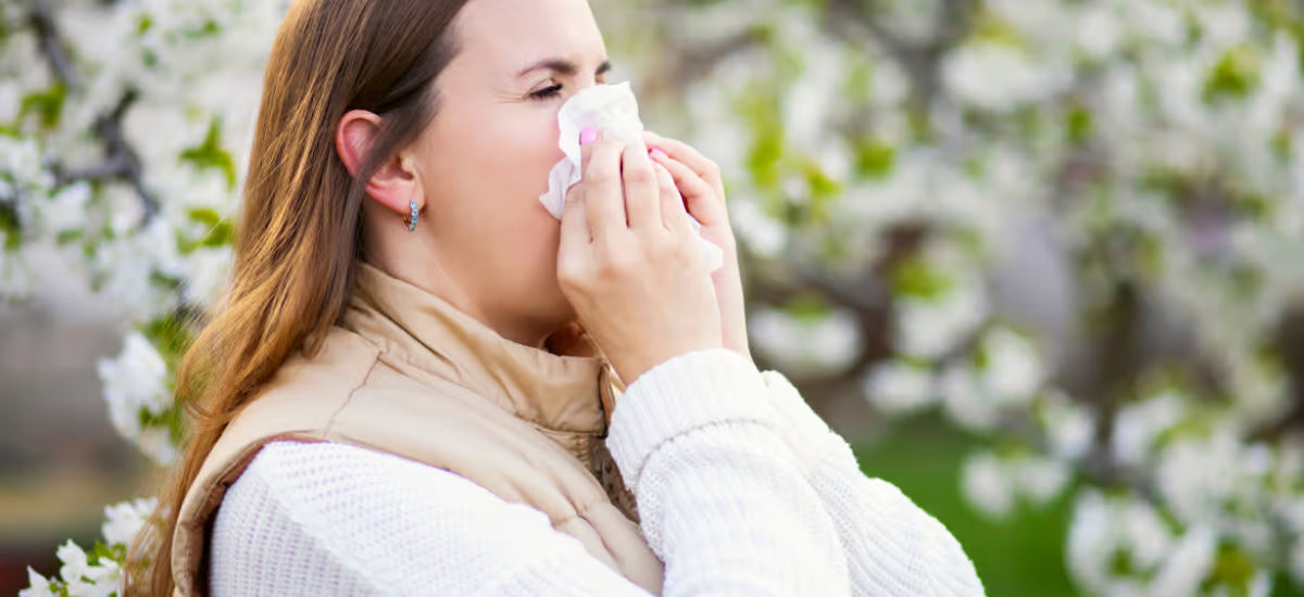 Eine Frau mit einer Pollenallergie putzt sich die Nase