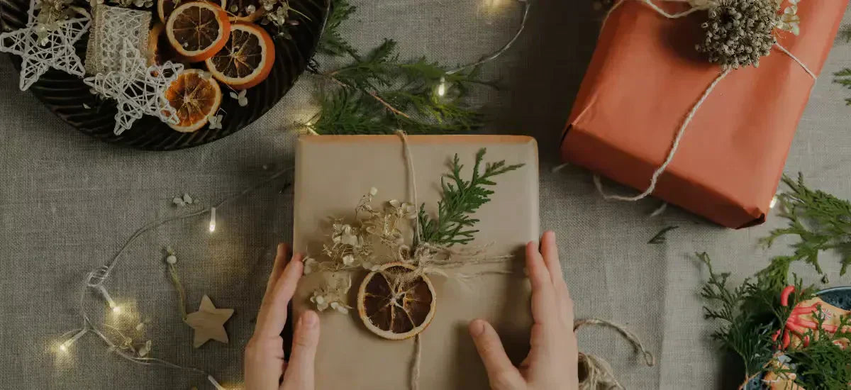 Hände, die ein natürlich dekoriertes Geschenk einpacken, perfekt für Weihnachtsgeschenke