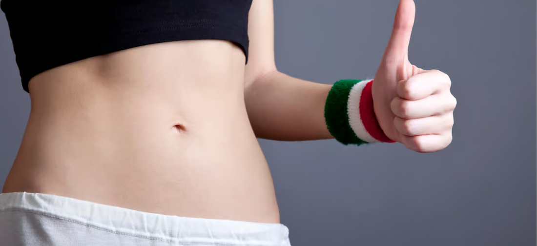 Frau zeigt entblößten Bauch und Daumen nach oben