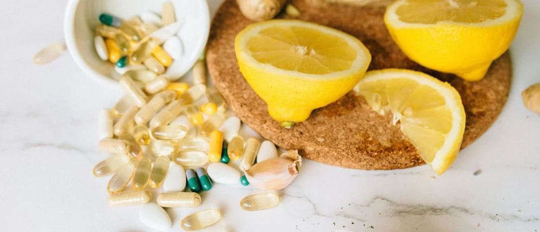 Nahrungsergänzungsmittel und Vitamine für das Immunsystem, verteilt auf einer Arbeitsfläche neben einer aufgeschnittenen Zitrone.