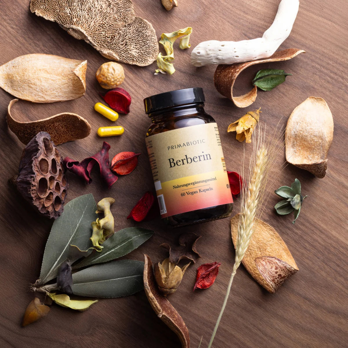 Verpackung Berberin von Primabiotic mit Kapseln, Kräutern und Pflanzenstücken auf Holzhintergrund