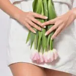 Frau in weißem Kleid hält Tulpen in Rosa