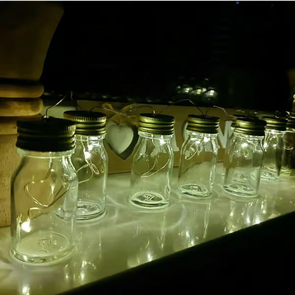 Glasflaschen mit Kollagen oder Primabiotic Hyaluronsäure, die als Laternen auf der Fensterbank stehen